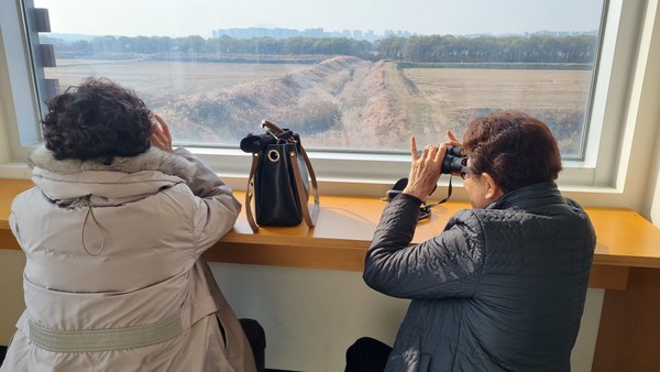 장항습지탐조대에서 해설사의 안내를 들으며 재두루미와 큰기러기를 바라보는 모습