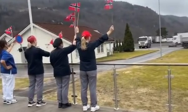 저속 주행 시위를 찬성하는 사람들이 노르웨이 국기를 들고 환영하고 있다.     노르웨이 공영방송 NRK 보도화면 캡처