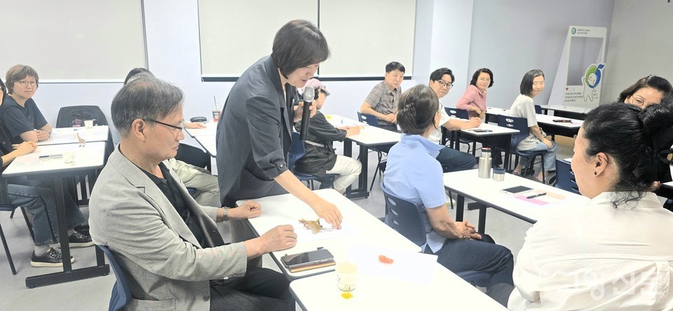 회원들이 강의실 뒤편에서 직관적으로 선택해 온 피규어에 담긴 무의식과 내면의 상태를 설명하자, 노미화 이사가 각 자리에 다가가 귀를 기울이며 소통을 이어가고 있다.