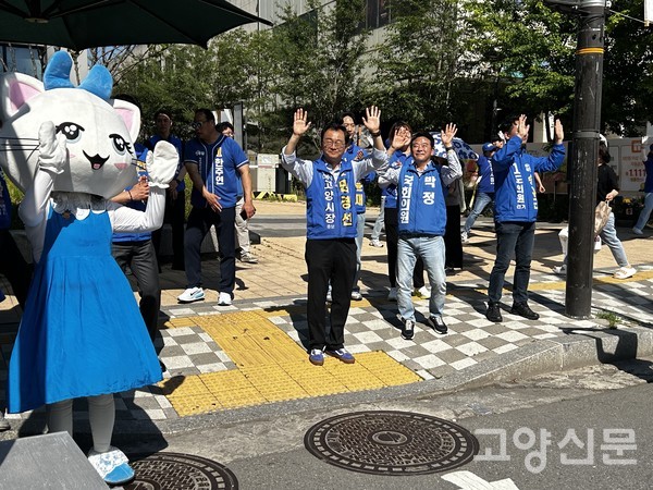 민경선 고양시장 후보와 박정 국회의원이 고양시 마스코트인 '고양고양이' 탈을 쓴 지지자와 함께 유세송에 맞춰 춤을 추고 있다.