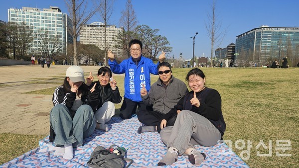일산호수공원 인근 잔디밭에서 시민들과 나란히 앉아 소통하며 '손가락 하트'를 그리는 이성한 당선인. 에코 트레일 코스 조성 등 그의 환경·문화 공약과 맞닿아 있는 친밀한 행보다.