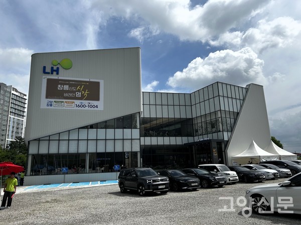 경기도 파주시 와동동에 마련된 LH 고양파주 주택전시관 전경. 외벽에는 '창릉신도시의 시작, 바라던 명작'이라는 대형 현수막이 걸려 있으나, 전시관 외부에서는 4년을 대기한 사전청약 당첨자들의 항의 집회가 이어지고 있다.