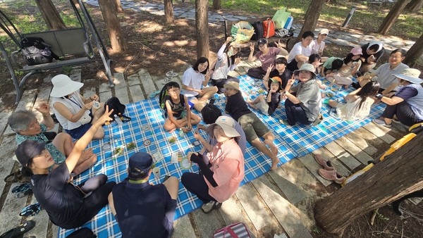고양아쿠아스튜디오 야외 숲그늘에서 만들기 체험을 하고 있는 참가자들.