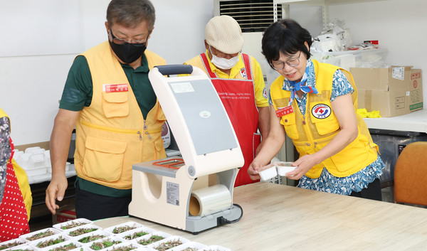 다 만들어진 반찬을 흐트러지지 않게 포장하는 박진수 전 회장(왼쪽)과 유순덕 현 회장