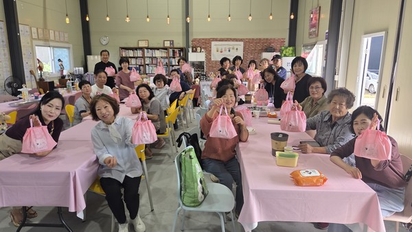 한국민속문화협회 회원들이 체험활동으로 만든 강정 꾸러미를 들고 기념촬영을 하고 있다.