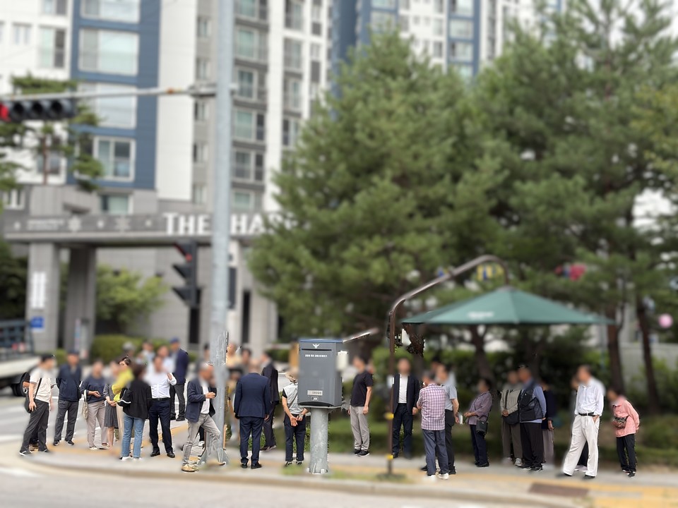 지난 10일 안양 평촌 현장을 찾은 식사동 주민들이 전문 기관인 미래전파공학연구소 안내에 따라 아파트 앞 지중선로 구간에 모여 실시간 전자파 수치를 확인하고 있다.