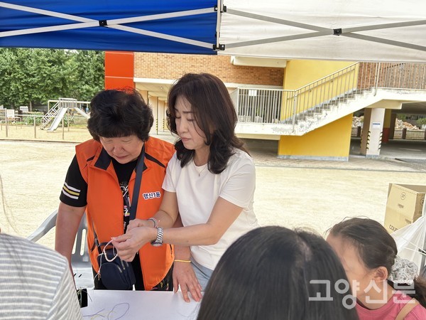 '학교 놀이공방' 구역에 마련된 부스에서 이해림 고양시의원이 지역 주민과 함께 매듭팔찌 만들기 체험에 참여하고 있다.