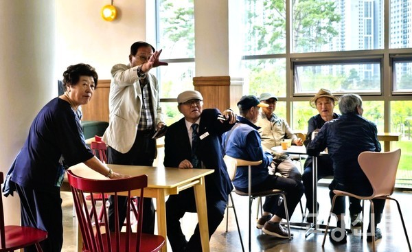 원주민 어르신들이 원탁에 둘러앉아 지축동에서의 옛 기억을 회상하며 대화하고 있다.