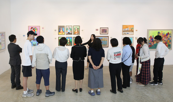 전시된 그림에 대해 설명을 듣는 참석자들.