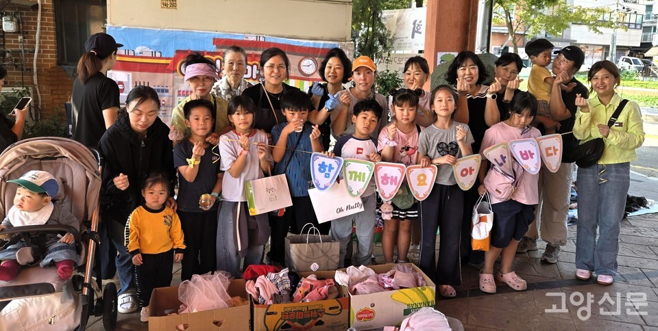 바자회를 함께 준비하고 운영한 사랑샘 지역아동센터와 가좌다솜어린이집 교직원, 학부모, 아이들이 '함께해요 아나바다' 문구를 들고 환한 미소로 기념 촬영을 하고 있다.