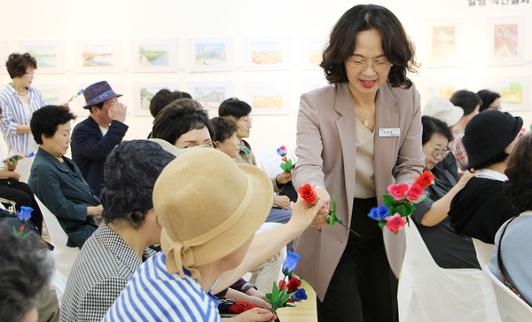 최윤정 관장이 개막식 퍼포먼스에서 참석자들에게 꽃을 전달하고 있다.