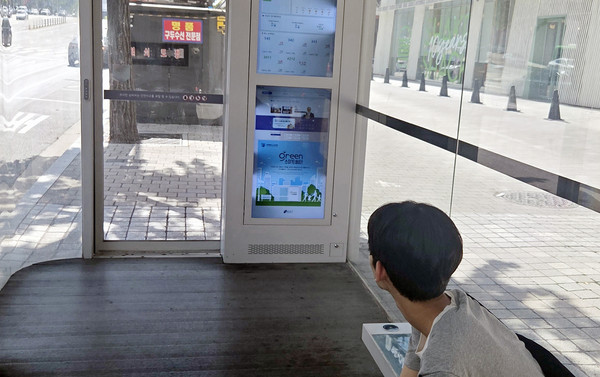  서울에 설치된 스마트 쉽터에서 윤호진 학생이 디지털 스크린의 정보를 보고있다.