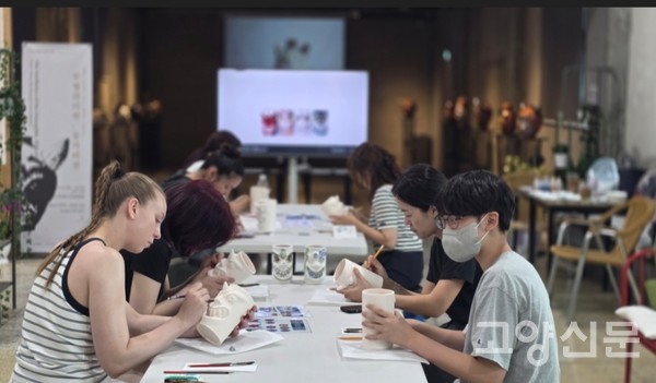 도자 관련 행사에서 초벌구이 도자에 그림작업 체험하는 관람객들
